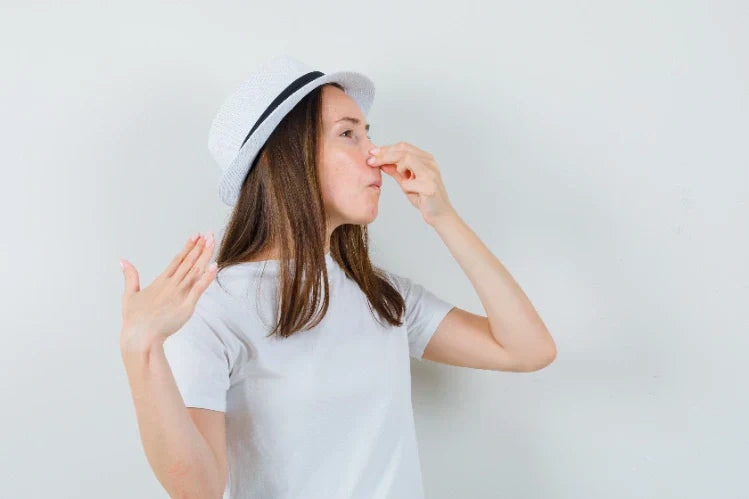 A young girl pinching her nose due to a bad smell