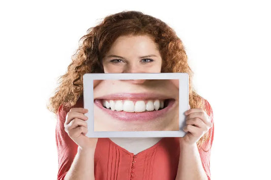 An image of a girl holding a zoomed-in image of her teeth