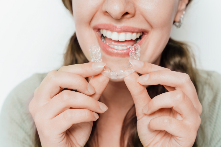 Young woman smiling with joy while holding clear aligners.