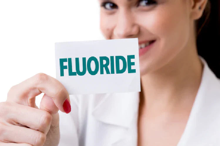 An image of a woman holding carding with fluoride written on it.