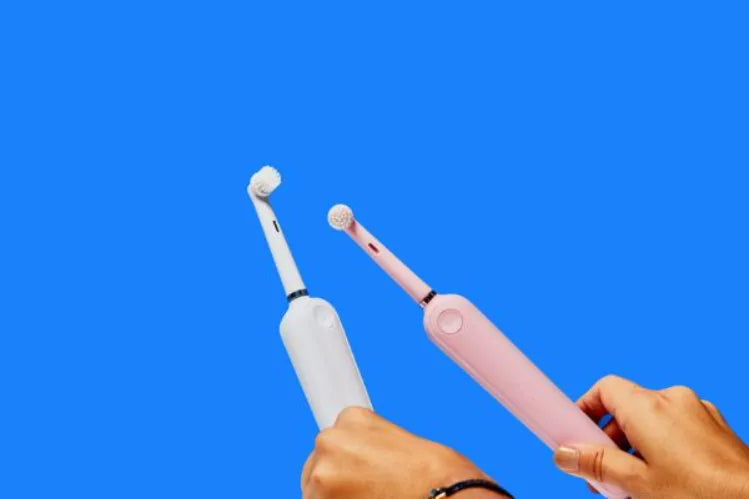 White and pink electric toothbrushes on a blue background