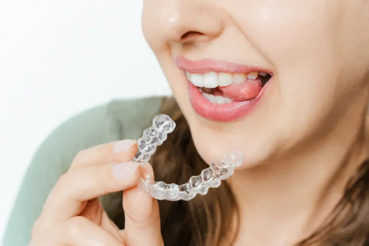 A girl is holding clear aligners