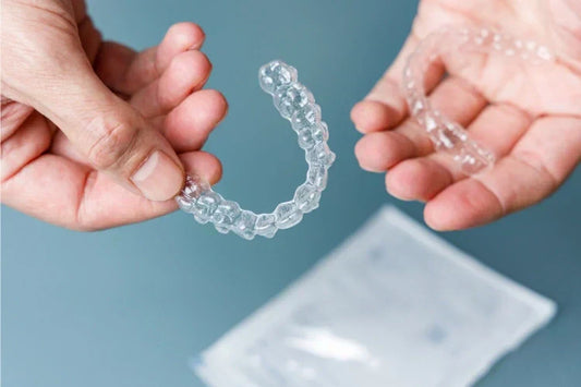 Hands holding a pair of clear aligners