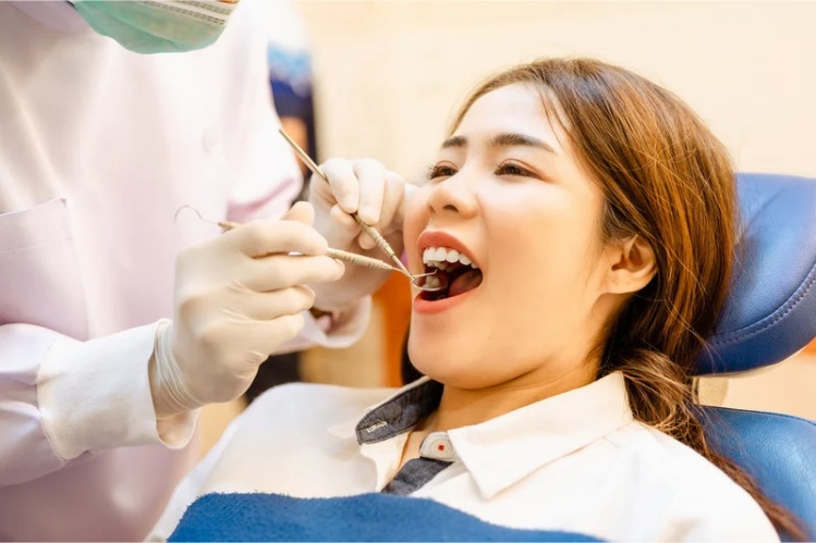 Dentist examining a young woman's teeth in a dental chair