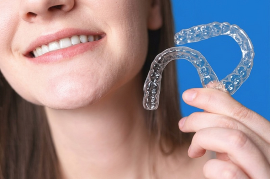 Smiling woman holding a clear aligner near her face