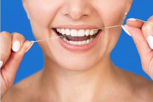 Smiling woman flossing her teeth on a blue background