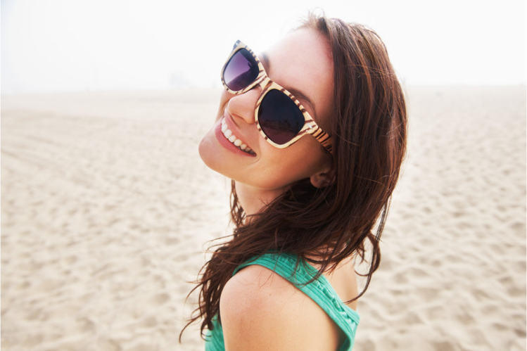 Smiling woman in sunglasses on a sunny beach