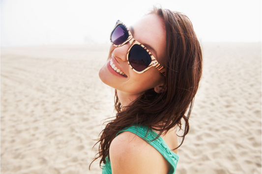 Smiling woman in sunglasses on a sunny beach