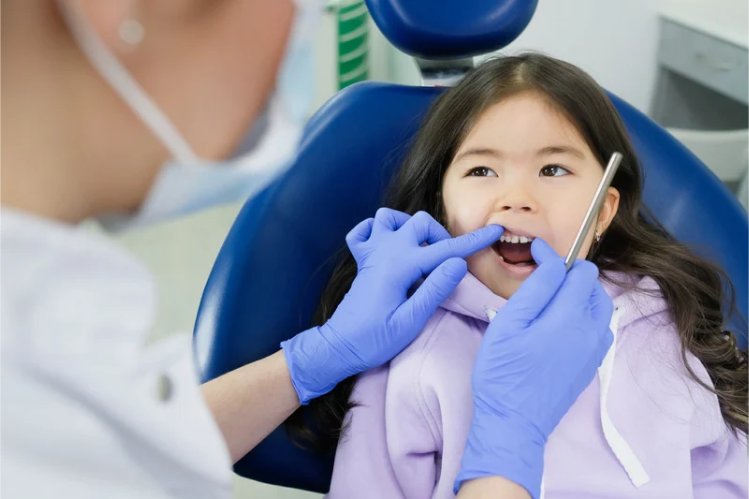 Dentist checking the teeth of a young girl in a dental chair