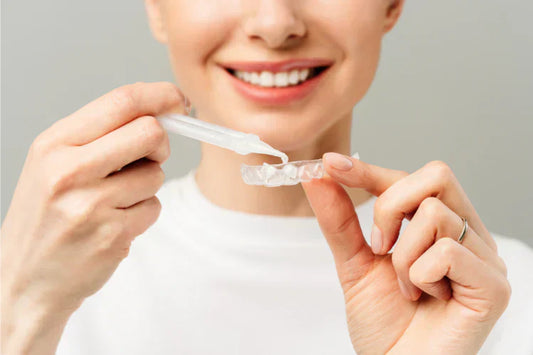 A woman putting teeth whitening gel into the aligner trays.