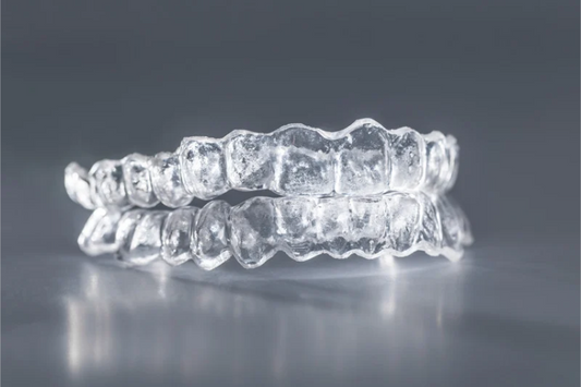 Close-up of stacked clear aligner trays on a dark grey surface