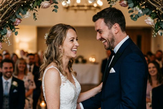 A bride and groom sharing a spontaneous, joyful laugh during their wedding ceremony.