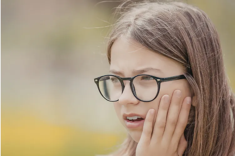  A girl holding her cheek in pain after a bite.