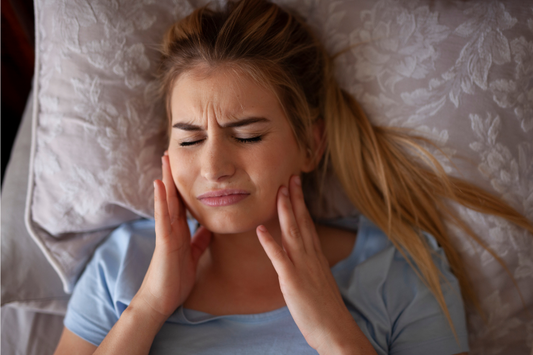 A girl is feeling jaw pain after waking up.