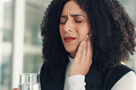 A woman holding her jaw due to TMJ pain 