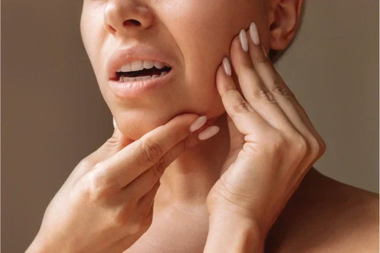 A woman is holding her jaw while suffering from jaw pain
