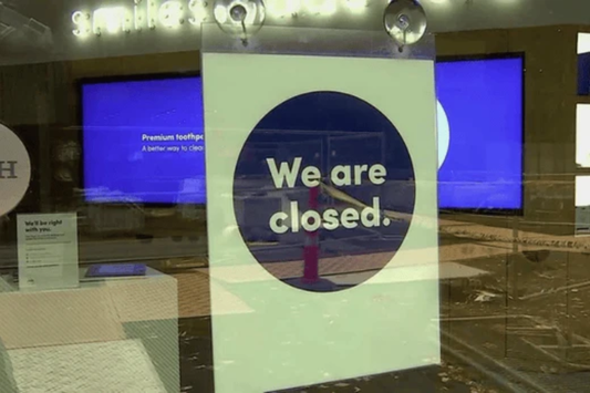 SmileDirectClub store window with a We Are Closed sign