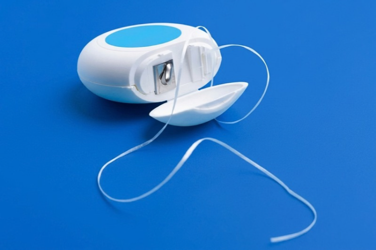Dental floss container with floss on a blue background