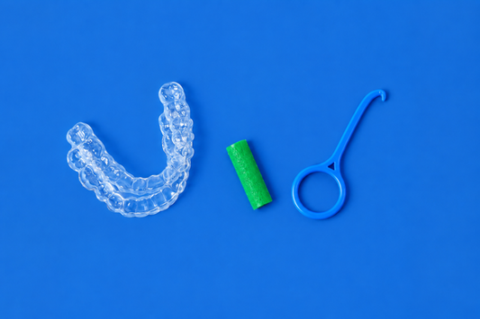 Clear aligner with a green chewie and removal tool on a blue background