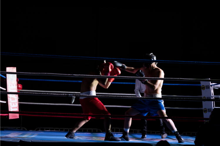 Two boxers sparring in a ring under dramatic lighting