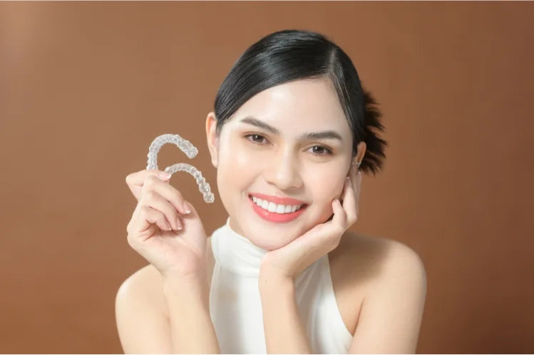 a beautiful woman with symmetrical features holding clear aligners 