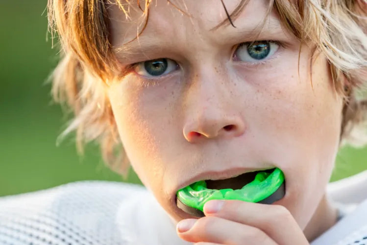 A boy putting in a sports mouth guard before the game.