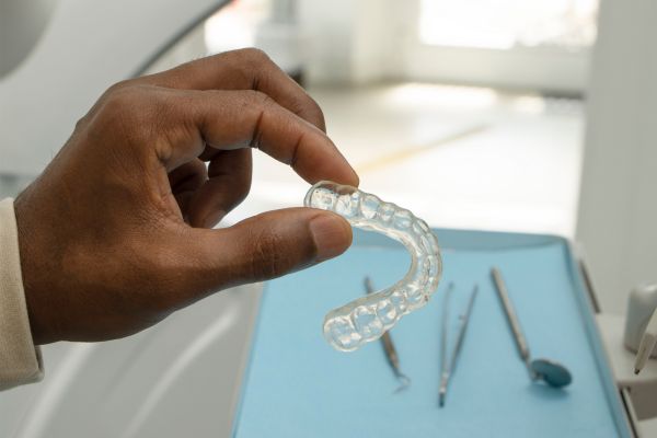 Dentist holding a clear retainer in his clinic